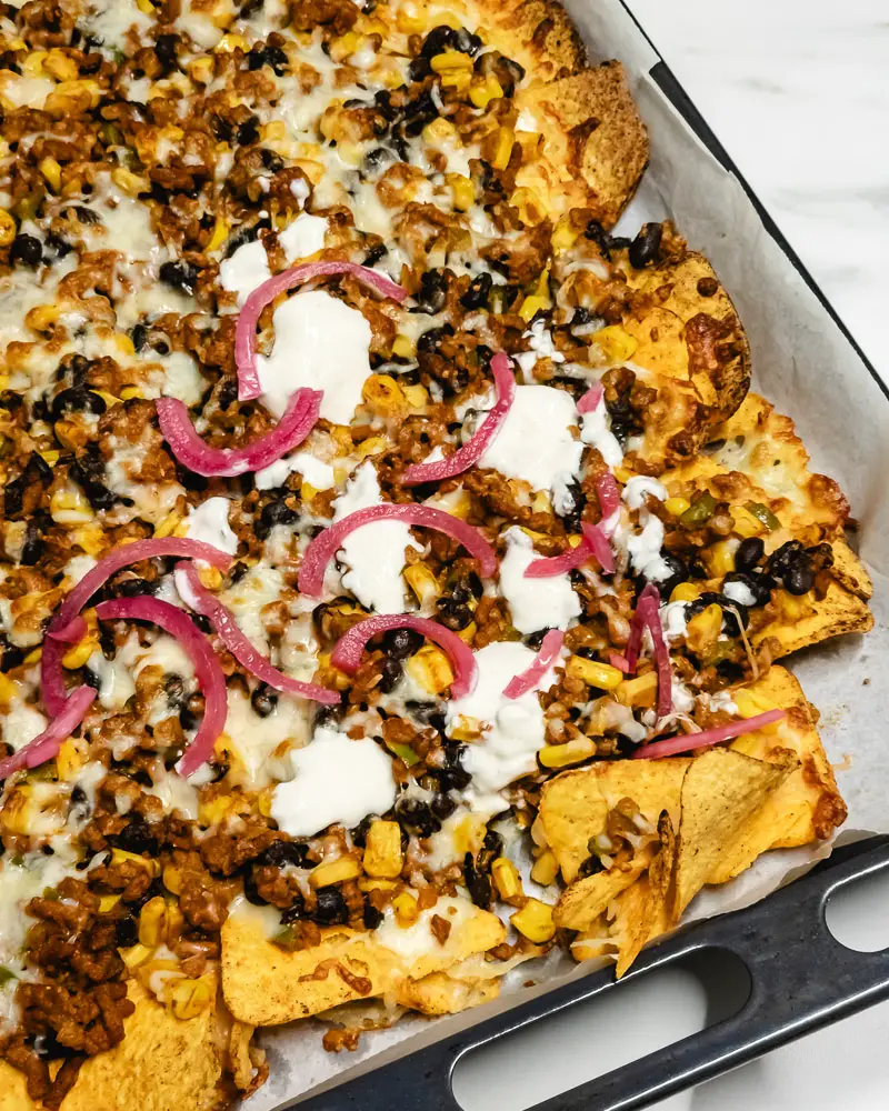 Nachos no forno: Tabuleiro acabado de sair do forno, com queijo derretido e as tortilhas crocantes.